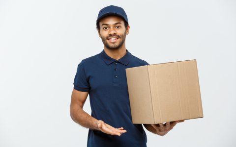 delivery-concept-portrait-happy-african-american-delivery-man-red-cloth-holding-box-package-isolated-grey-studio-background-copy-space